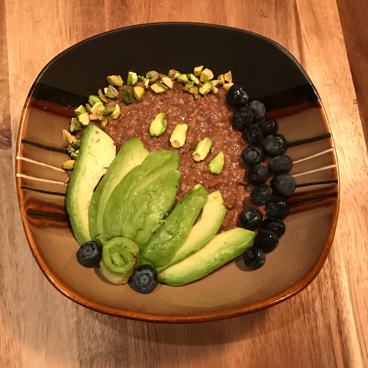 Chocolate oatmeal with pistachios, blueberries and avocado